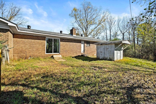 rear view of house with a yard and a storage unit