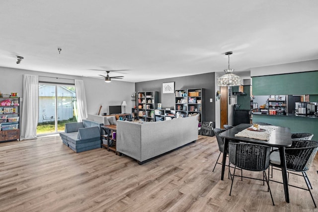 living room featuring ceiling fan with notable chandelier and light wood-type flooring