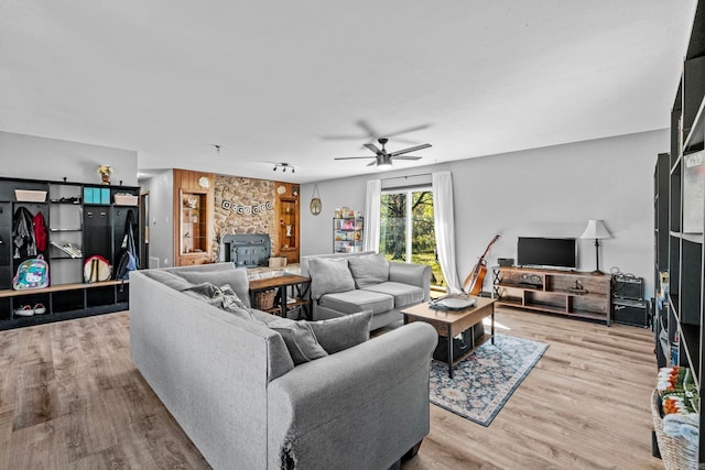 living room featuring a wood stove, ceiling fan, and light hardwood / wood-style floors