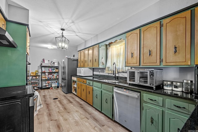 kitchen with appliances with stainless steel finishes, sink, decorative light fixtures, an inviting chandelier, and light hardwood / wood-style floors