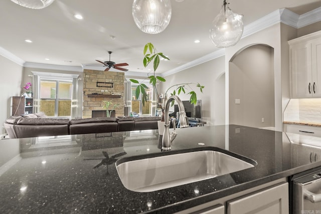 kitchen with white cabinets, ornamental molding, sink, and dark stone counters