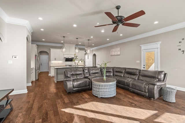 living room with dark hardwood / wood-style floors, ceiling fan, and ornamental molding