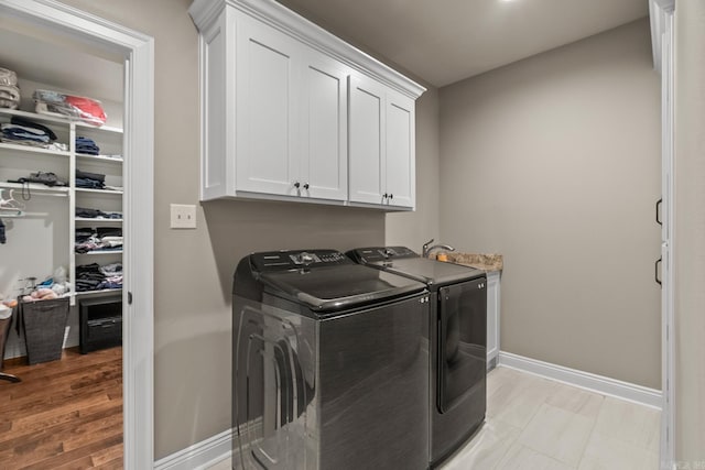 laundry room with light hardwood / wood-style floors, cabinets, and independent washer and dryer