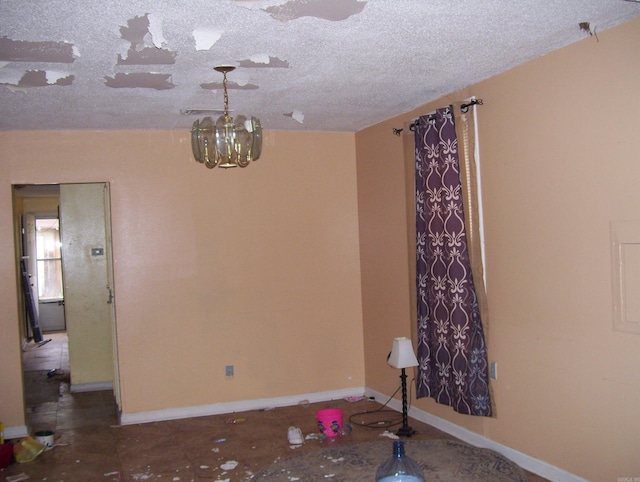 empty room featuring a textured ceiling and an inviting chandelier