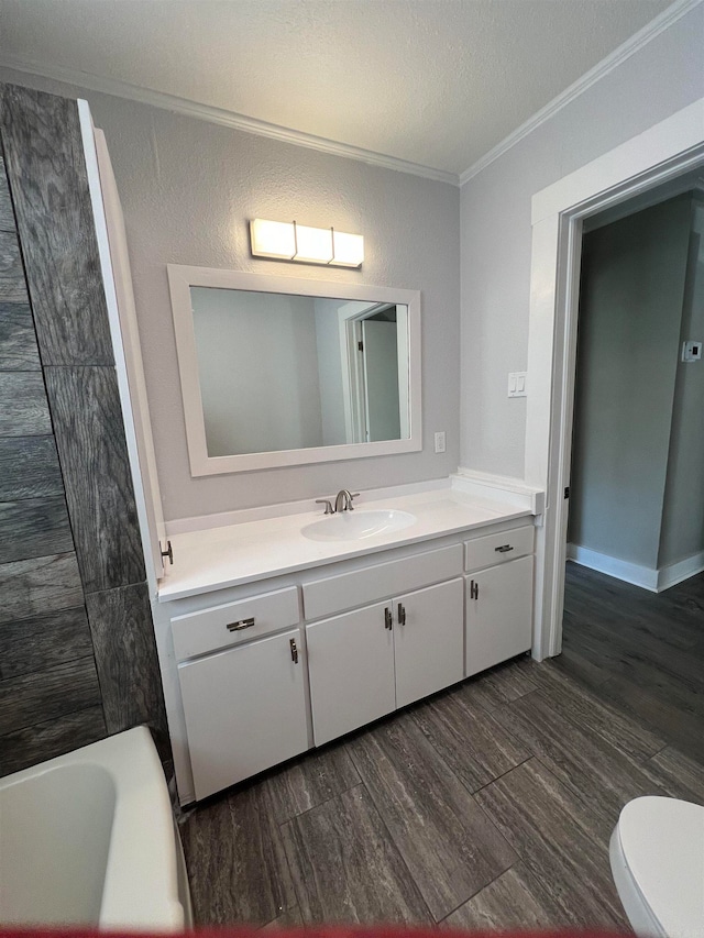 bathroom with crown molding, hardwood / wood-style floors, a textured ceiling, toilet, and vanity