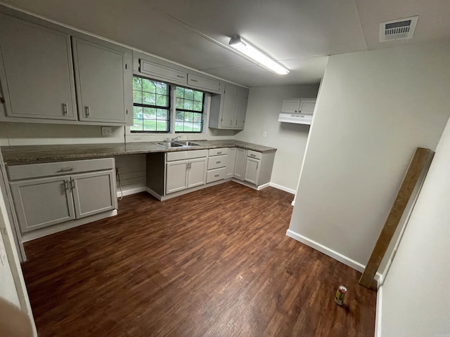 kitchen with gray cabinetry, dark hardwood / wood-style floors, sink, and stone counters