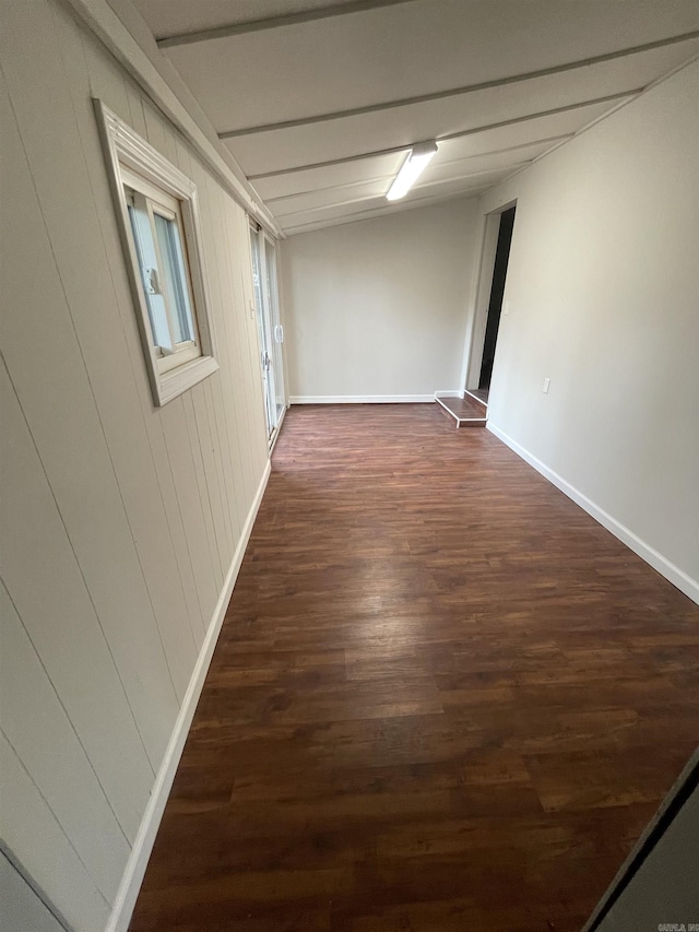 unfurnished room featuring wooden walls and dark wood-type flooring