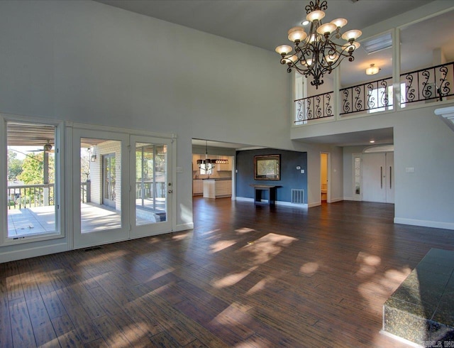 unfurnished living room featuring dark hardwood / wood-style floors, a chandelier, and a high ceiling