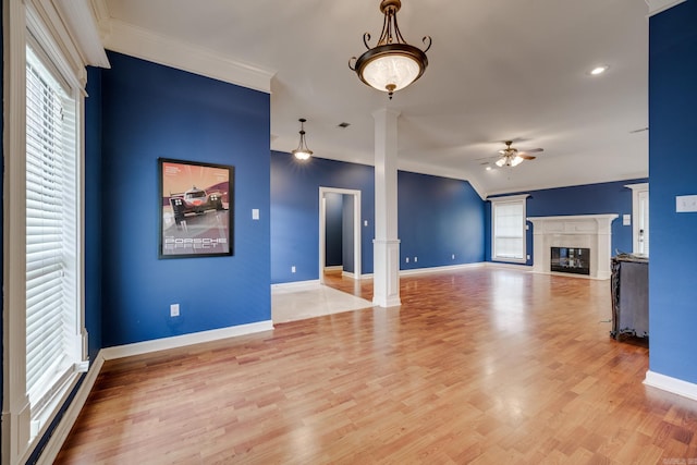 unfurnished living room with ornate columns, plenty of natural light, vaulted ceiling, and light wood-type flooring