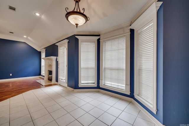 unfurnished living room featuring a high end fireplace, light hardwood / wood-style floors, crown molding, and lofted ceiling