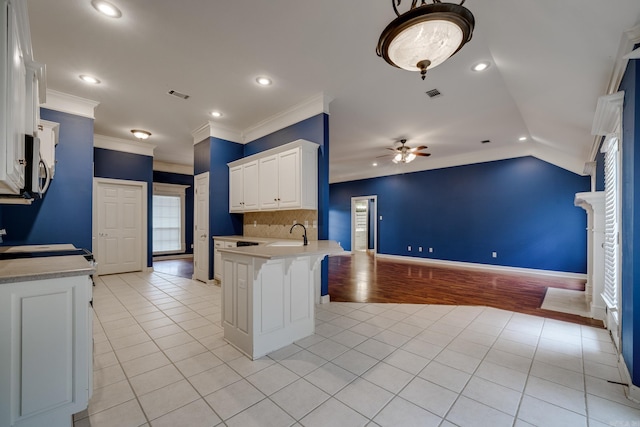 kitchen featuring sink, ornamental molding, light hardwood / wood-style floors, a kitchen bar, and white cabinetry