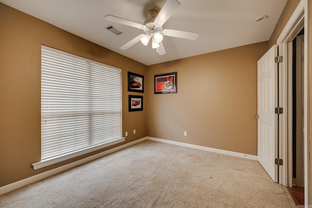 spare room featuring a wealth of natural light, ceiling fan, and light colored carpet