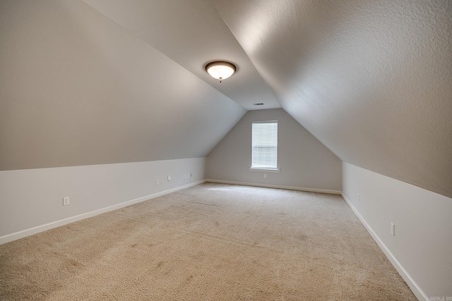 bonus room with a textured ceiling, light colored carpet, and vaulted ceiling