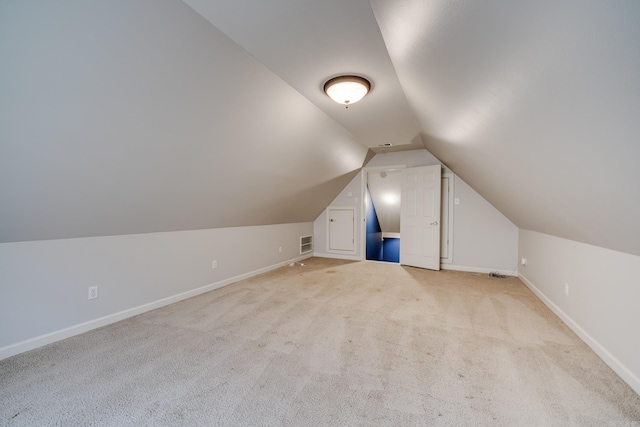 additional living space featuring light colored carpet and vaulted ceiling