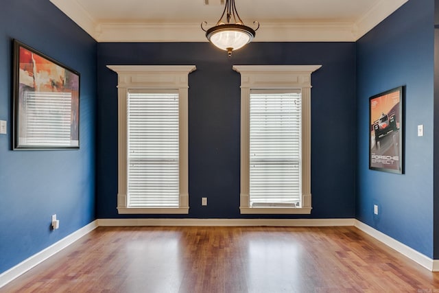 empty room with hardwood / wood-style floors and crown molding