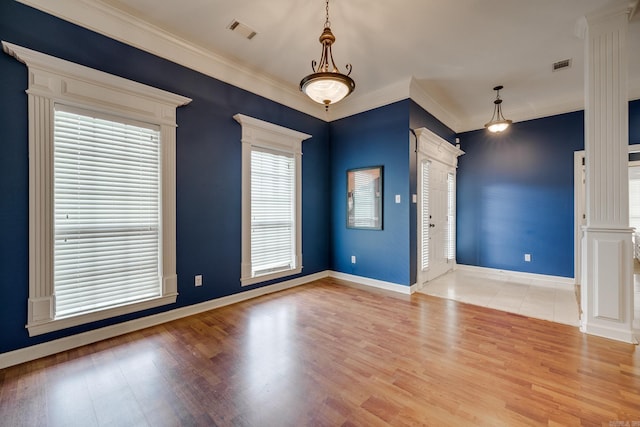 spare room featuring light hardwood / wood-style flooring, ornamental molding, and ornate columns