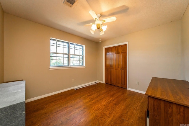 unfurnished bedroom with a textured ceiling, ceiling fan, a closet, and dark hardwood / wood-style floors