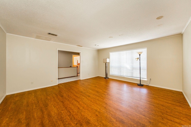 empty room with ornamental molding, a textured ceiling, and hardwood / wood-style flooring