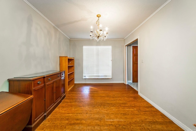 dining area with wood-type flooring, crown molding, and an inviting chandelier