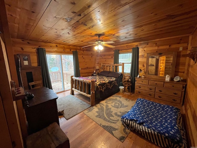 bedroom featuring access to exterior, wood ceiling, ceiling fan, wooden walls, and hardwood / wood-style floors