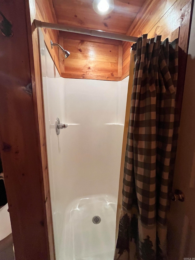 bathroom with a shower with curtain, wooden walls, and wood ceiling