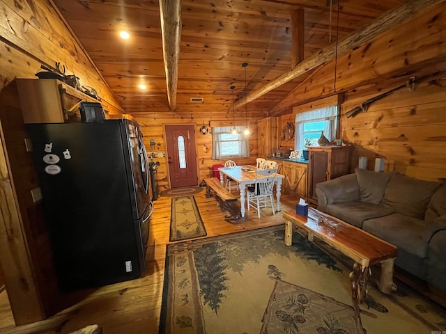 kitchen with wooden ceiling, lofted ceiling with beams, black fridge, wooden walls, and light hardwood / wood-style flooring