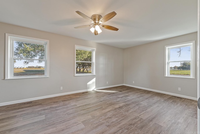 unfurnished room featuring ceiling fan, light wood-type flooring, and a wealth of natural light