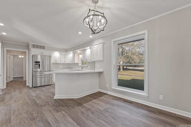 kitchen featuring white cabinetry, light hardwood / wood-style flooring, stainless steel refrigerator with ice dispenser, kitchen peninsula, and decorative light fixtures