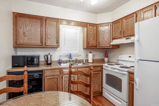 kitchen with sink, black appliances, a textured ceiling, and light hardwood / wood-style floors