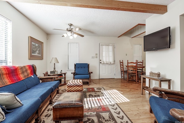 living room featuring beam ceiling, ceiling fan, a textured ceiling, and light wood-type flooring