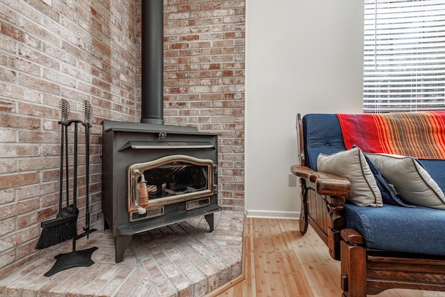 interior space featuring hardwood / wood-style floors, a wood stove, and brick wall