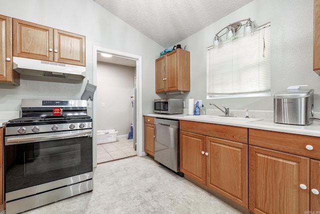 kitchen featuring a textured ceiling, sink, vaulted ceiling, and appliances with stainless steel finishes