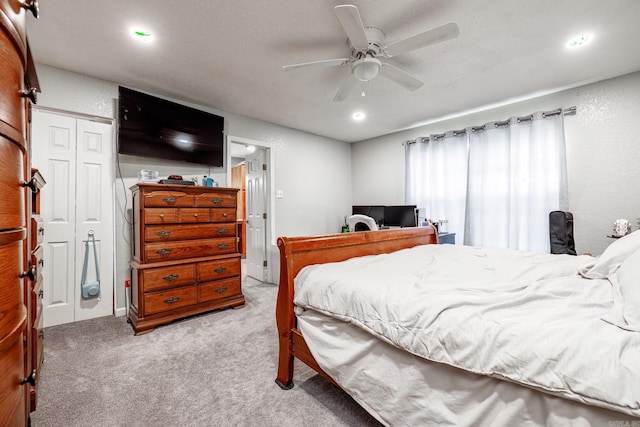 bedroom featuring a textured ceiling, ceiling fan, light carpet, and a closet