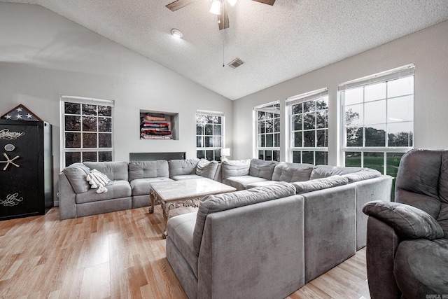 living room with a textured ceiling, light hardwood / wood-style floors, high vaulted ceiling, and ceiling fan