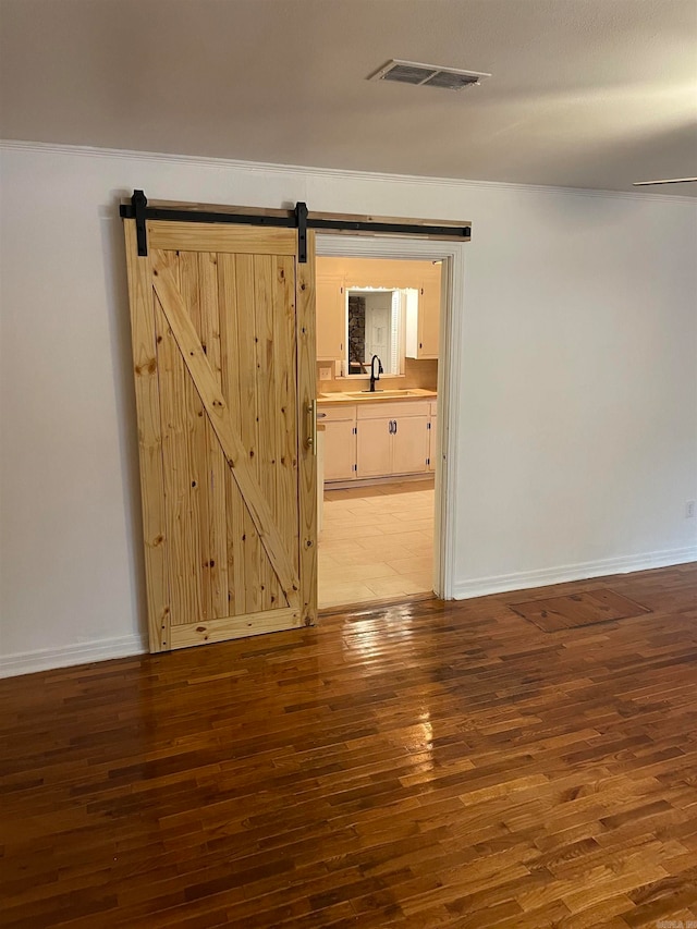 empty room featuring a barn door, dark hardwood / wood-style floors, and sink