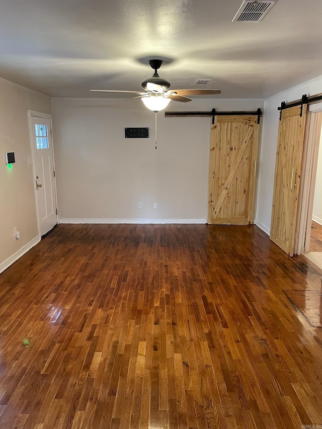 spare room featuring dark hardwood / wood-style flooring, a barn door, and ceiling fan