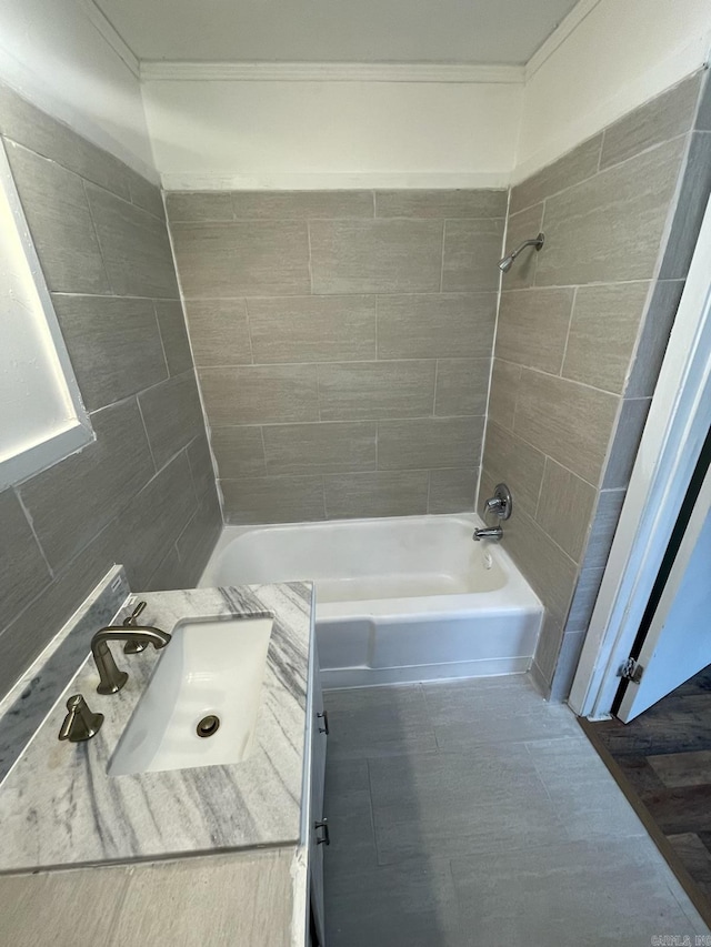 bathroom featuring tile walls, tiled shower / bath, and sink