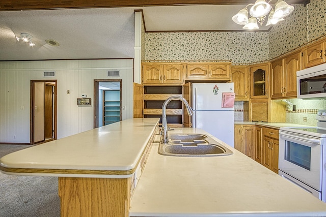 kitchen with a textured ceiling, crown molding, white appliances, and an island with sink