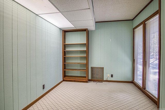 carpeted spare room featuring wooden walls and ornamental molding