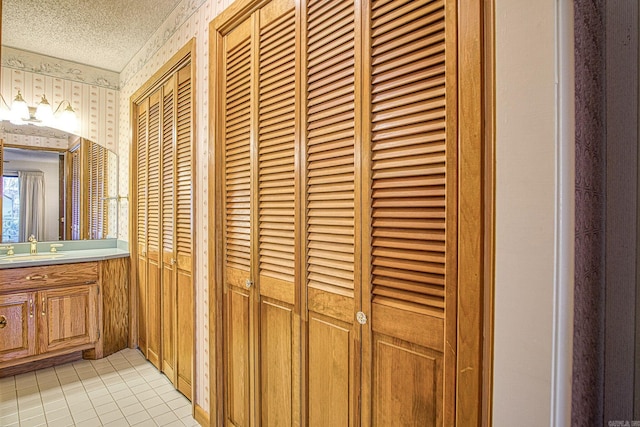 room details with tile patterned floors, vanity, and a textured ceiling