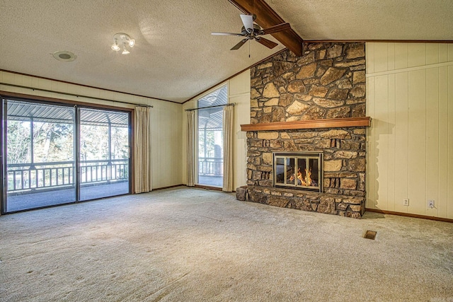 unfurnished living room with carpet flooring, a textured ceiling, a stone fireplace, and wooden walls