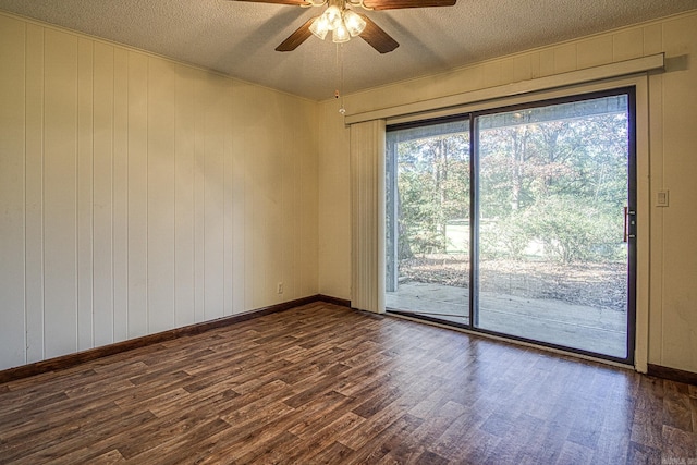 spare room with a textured ceiling, dark hardwood / wood-style flooring, ceiling fan, and wood walls