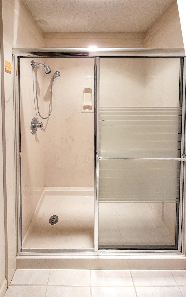 bathroom with tile patterned floors, a textured ceiling, and an enclosed shower