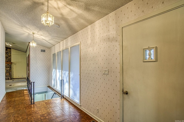 hall featuring dark parquet floors, lofted ceiling, and a textured ceiling