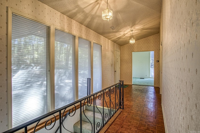 corridor featuring dark parquet flooring, lofted ceiling, a textured ceiling, and a chandelier