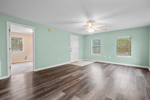 spare room featuring a healthy amount of sunlight, ceiling fan, and dark wood-type flooring