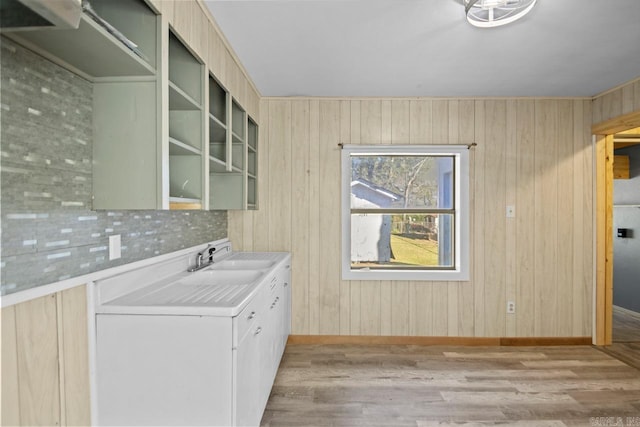 laundry room with wooden walls, sink, and light hardwood / wood-style flooring