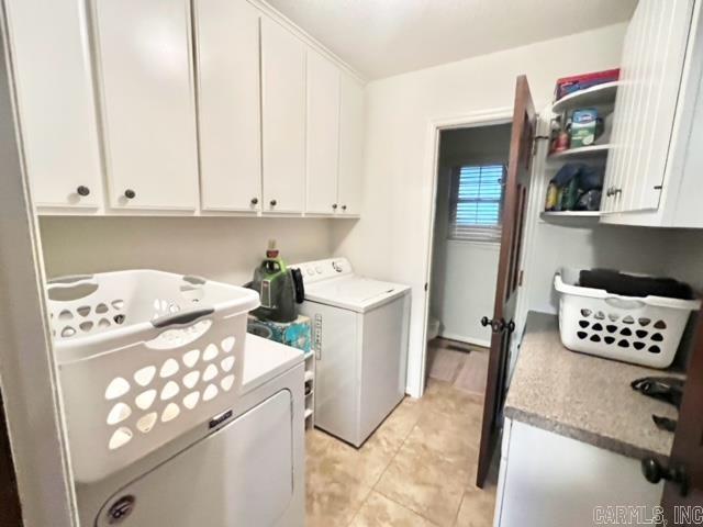 washroom featuring cabinets, light tile patterned floors, and washing machine and clothes dryer