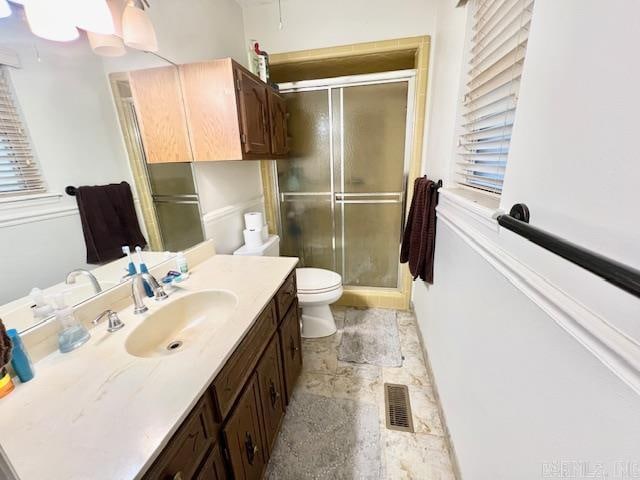 bathroom with a shower with door, vanity, and toilet