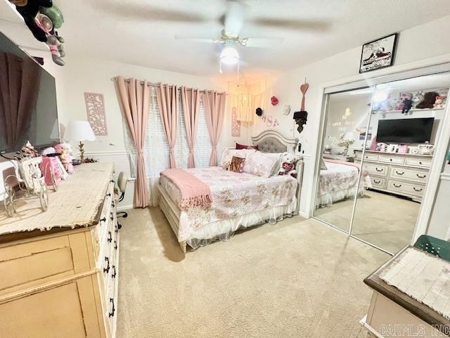 bedroom featuring ceiling fan, light colored carpet, and a closet